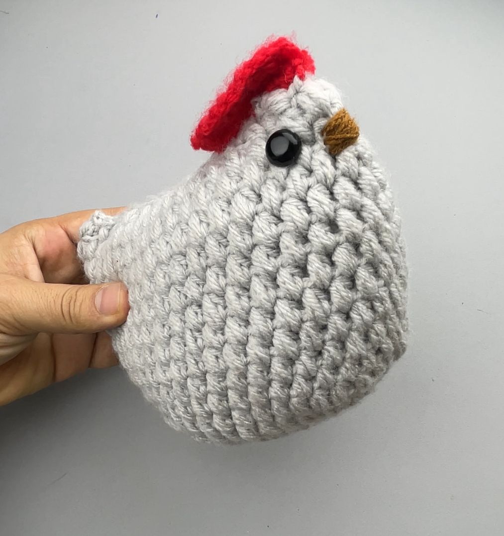White crochet amigurumi hen held in a hand